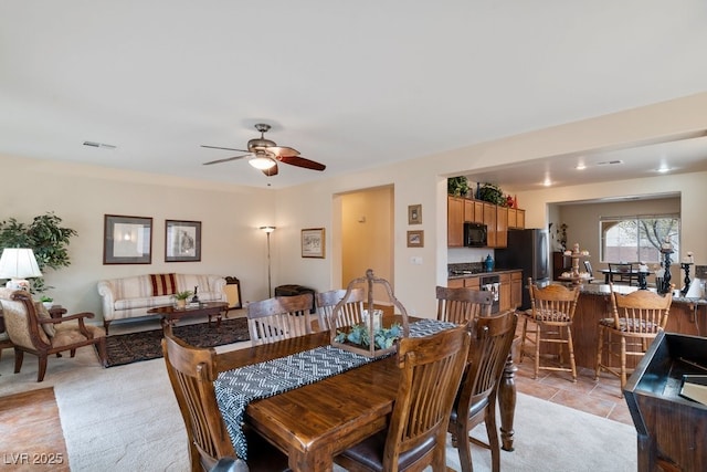 dining area with visible vents, light colored carpet, and ceiling fan