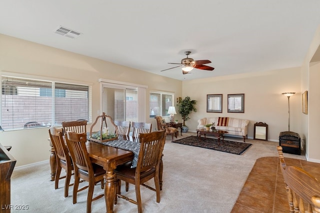 dining space with baseboards, light colored carpet, visible vents, and ceiling fan