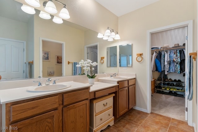 bathroom featuring double vanity, tile patterned flooring, a walk in closet, and a sink