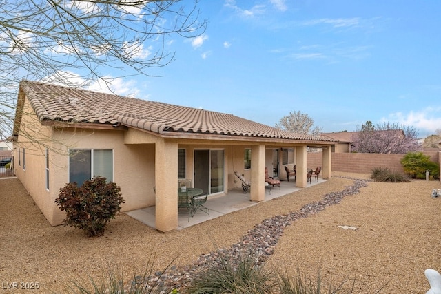 rear view of property featuring a patio area, a tiled roof, fence, and stucco siding