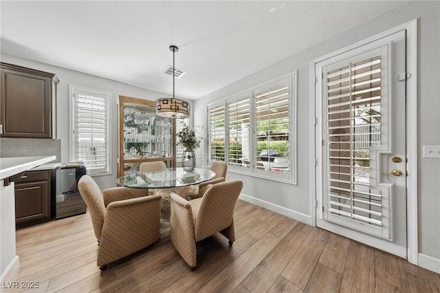 dining room with light wood finished floors, visible vents, and baseboards