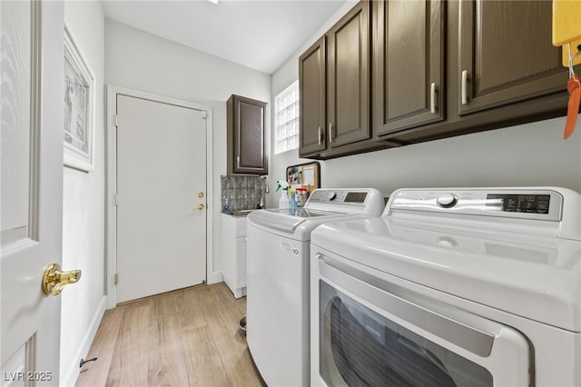 washroom with cabinet space, light wood-style flooring, and separate washer and dryer