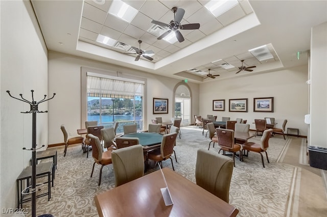 dining room with arched walkways, a raised ceiling, visible vents, a ceiling fan, and baseboards