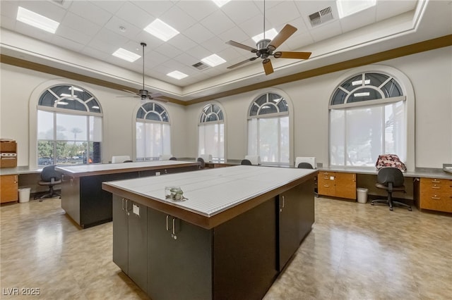 kitchen featuring a tray ceiling, tile countertops, visible vents, built in study area, and a kitchen island