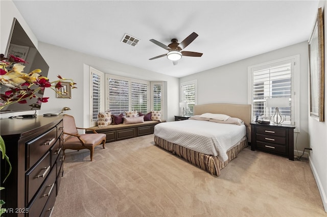 bedroom with a ceiling fan, light colored carpet, visible vents, and baseboards