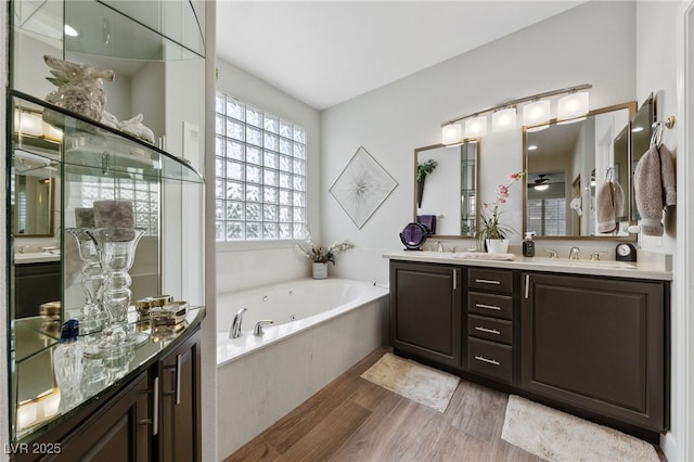 full bathroom with a sink, wood finished floors, a whirlpool tub, double vanity, and a stall shower