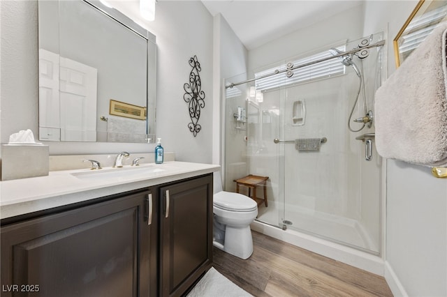 full bath with a stall shower, vanity, toilet, and wood finished floors