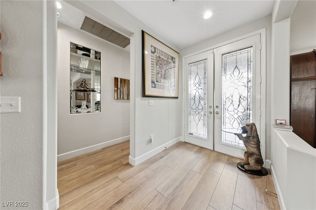 foyer featuring french doors, plenty of natural light, and wood finished floors