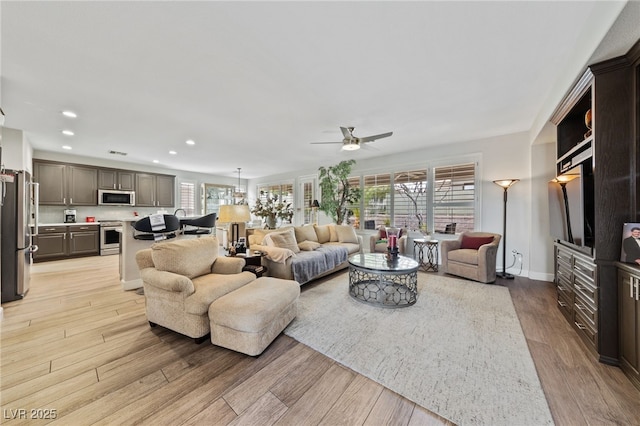 living room featuring light wood-type flooring, a healthy amount of sunlight, baseboards, and recessed lighting