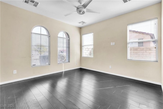 spare room featuring dark wood-style flooring, visible vents, and baseboards