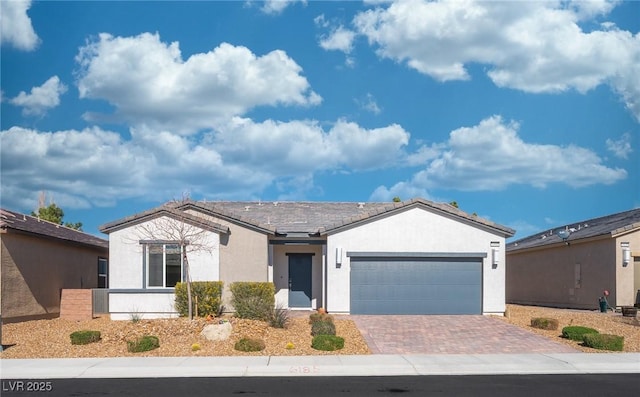 ranch-style house featuring decorative driveway, an attached garage, and stucco siding