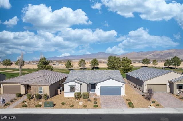 exterior space with an attached garage, a mountain view, decorative driveway, and stucco siding