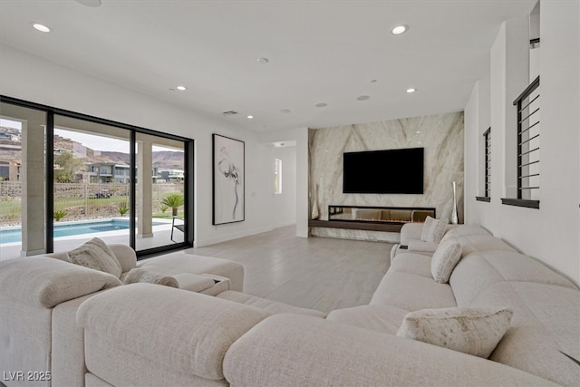 living room featuring light wood finished floors, recessed lighting, a premium fireplace, an accent wall, and baseboards