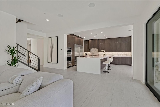 living room featuring stairs, baseboards, and recessed lighting