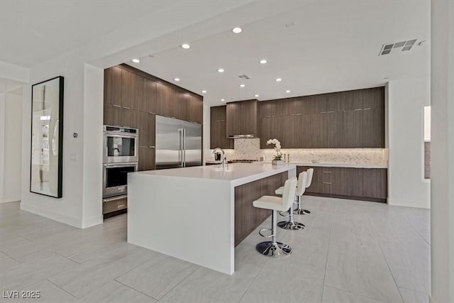 kitchen featuring visible vents, modern cabinets, a breakfast bar, stainless steel appliances, and light countertops