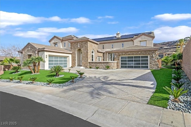 view of front of house featuring an attached garage, stone siding, driveway, and a front lawn