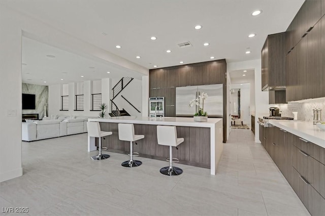 kitchen featuring a kitchen bar, stainless steel refrigerator, and modern cabinets