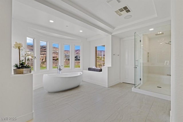 bathroom with a freestanding tub, visible vents, baseboards, a tray ceiling, and a stall shower