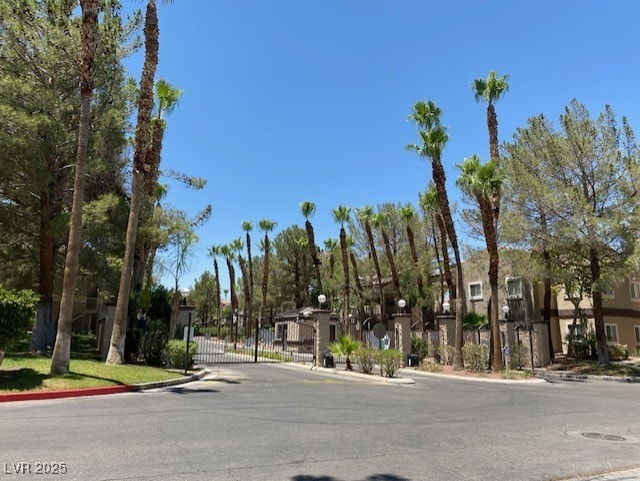 view of road with a gated entry, a residential view, a gate, and curbs