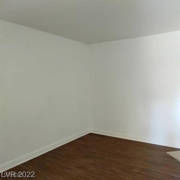 spare room with dark wood-type flooring and baseboards