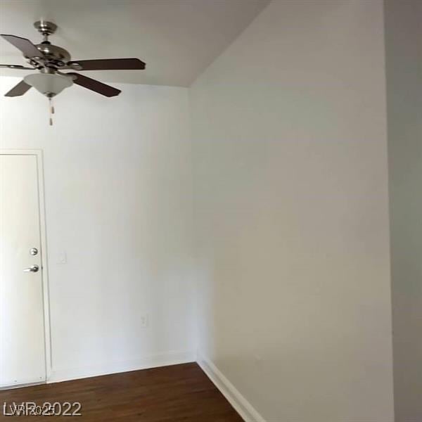 empty room featuring a ceiling fan, baseboards, and dark wood-type flooring