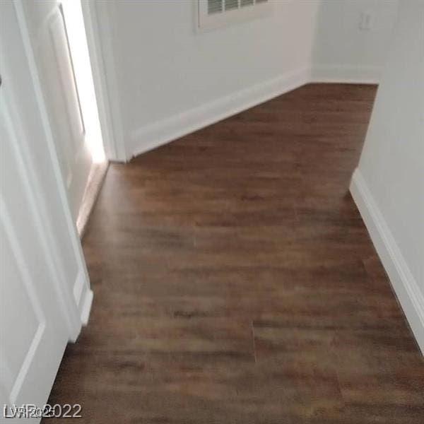 unfurnished room featuring baseboards, visible vents, and dark wood-type flooring