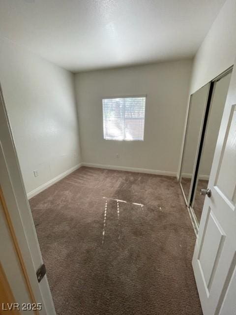 unfurnished bedroom with a closet, carpet flooring, and baseboards