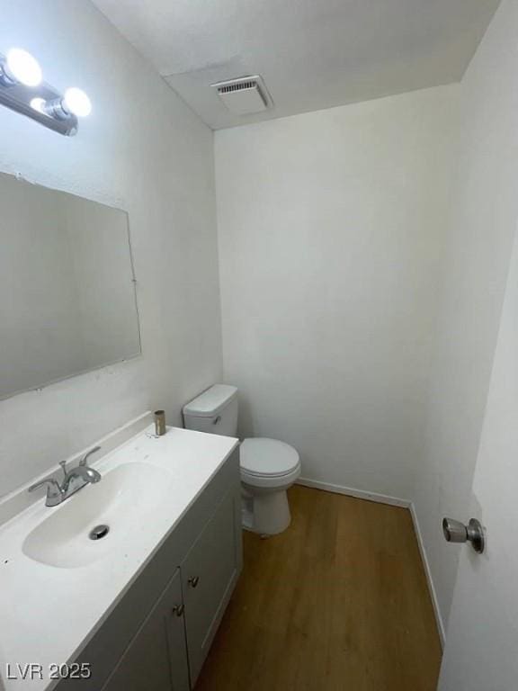 bathroom with visible vents, vanity, toilet, and wood finished floors