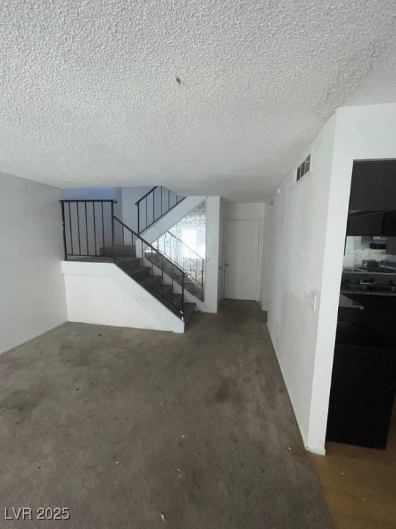 living area with stairs, a textured ceiling, and visible vents