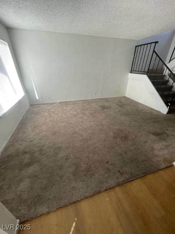 spare room with a textured ceiling, stairway, wood finished floors, and carpet flooring