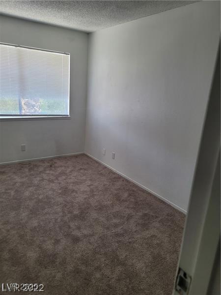 unfurnished room with a textured ceiling and carpet floors