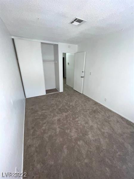 unfurnished bedroom with a closet, carpet flooring, visible vents, and a textured ceiling