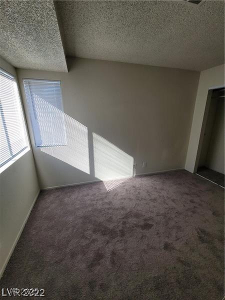 unfurnished room featuring a textured ceiling and carpet