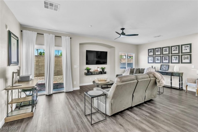 living room featuring baseboards, wood finished floors, visible vents, and a ceiling fan