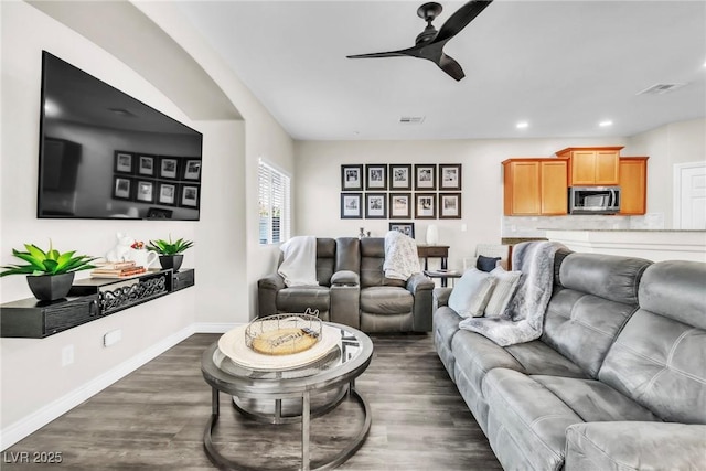 living area featuring visible vents, dark wood finished floors, and baseboards