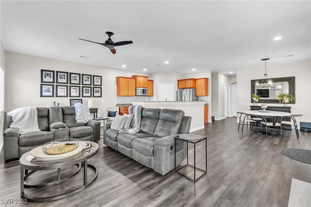 living room featuring dark wood-style floors, ceiling fan with notable chandelier, and recessed lighting