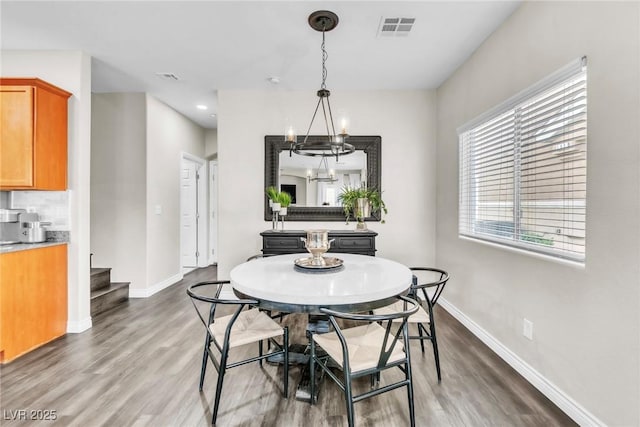 dining room with an inviting chandelier, visible vents, baseboards, and wood finished floors