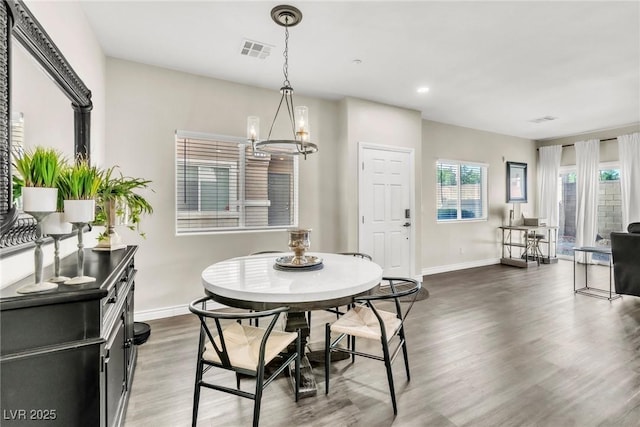 dining space featuring a notable chandelier, wood finished floors, visible vents, and baseboards