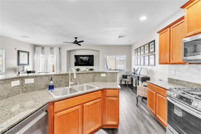 kitchen with light wood finished floors, stainless steel appliances, visible vents, open floor plan, and a sink