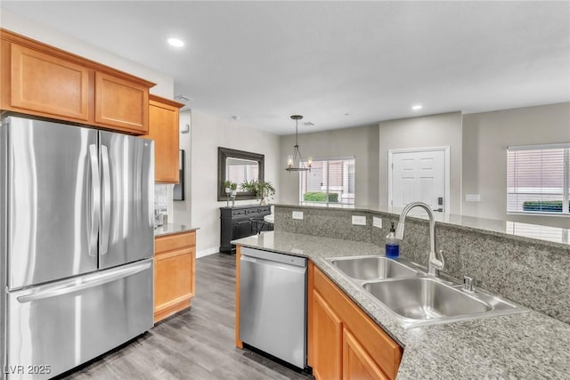 kitchen with light wood finished floors, stainless steel appliances, recessed lighting, a sink, and a chandelier