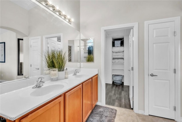 bathroom with a closet, double vanity, a sink, and tile patterned floors