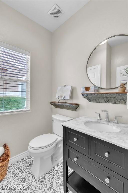 bathroom featuring baseboards, visible vents, toilet, tile patterned floors, and vanity