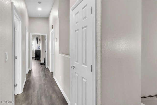 hallway with dark wood-style flooring and baseboards