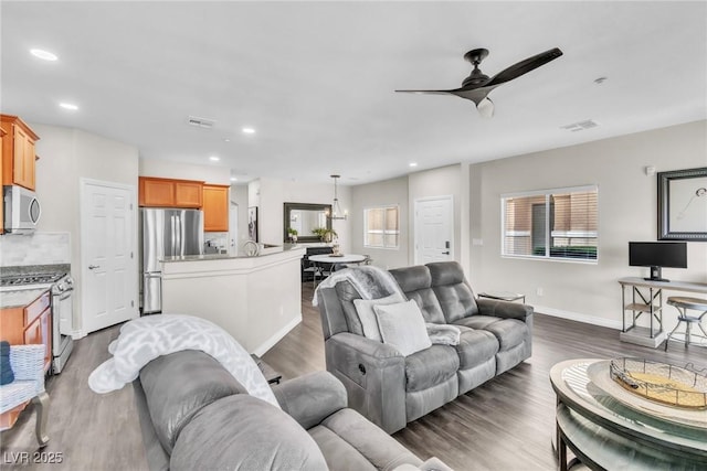 living room featuring dark wood-style flooring, visible vents, and ceiling fan