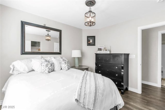 bedroom featuring baseboards, wood finished floors, and a notable chandelier