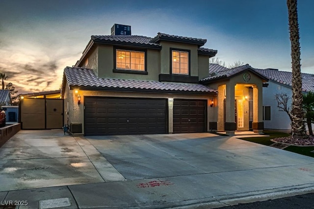 mediterranean / spanish-style home with a garage, stucco siding, driveway, and a tile roof