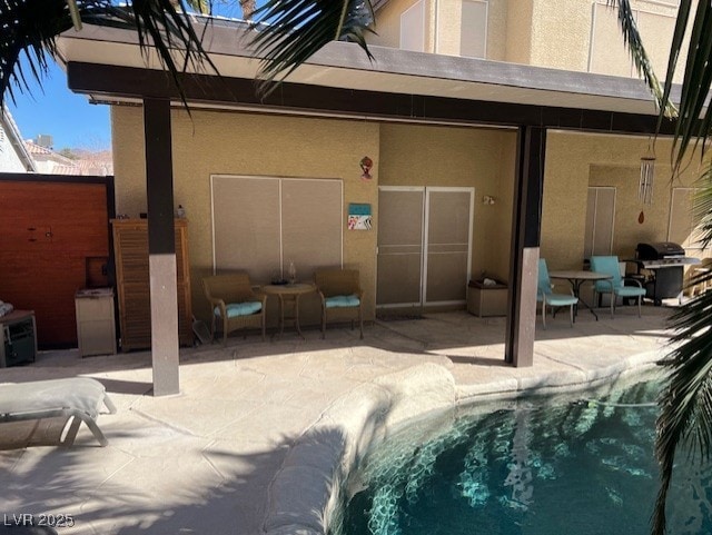 rear view of house with an outdoor pool, stucco siding, and a patio area