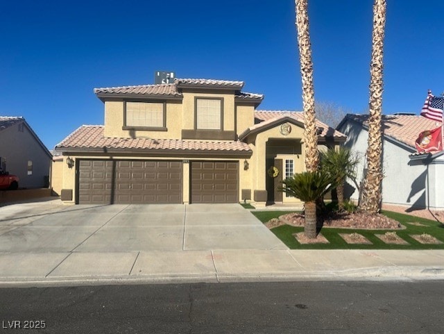 mediterranean / spanish house with a tile roof, concrete driveway, an attached garage, and stucco siding