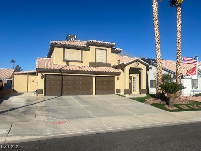 mediterranean / spanish house with stucco siding, concrete driveway, an attached garage, and a tiled roof