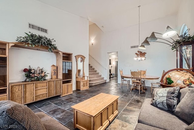 living room featuring stairs, visible vents, and stone tile flooring